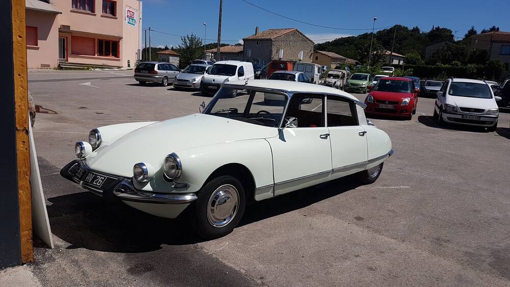 Une Citroën DS blanche à toit noir sur le parking du garage