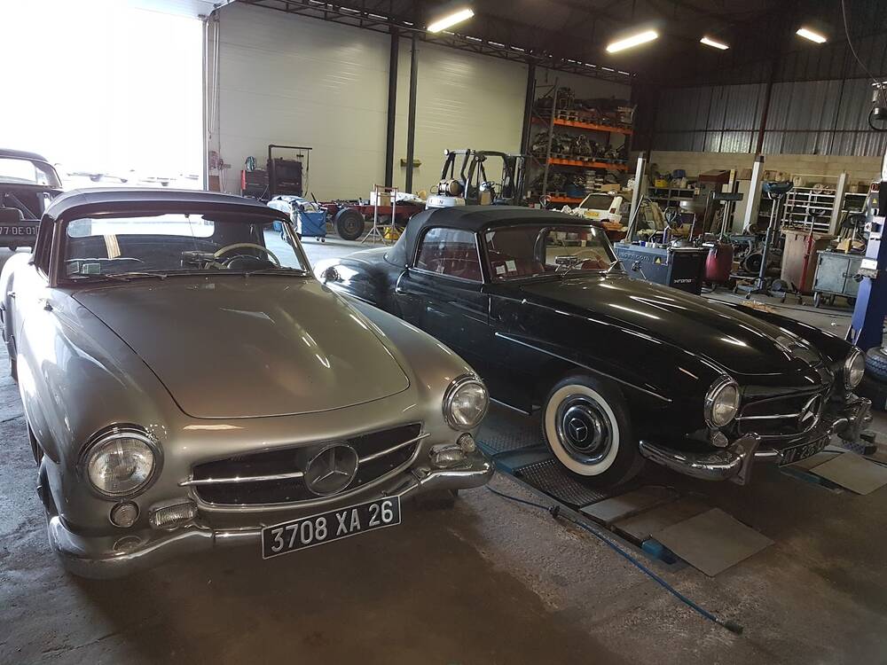 Deux cabriolets Mercedes anciens, un gris et un noir, dans l'atelier