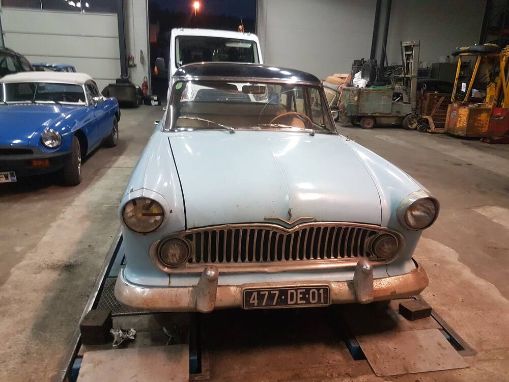 Une Simca bleu clair des années 50 posée sur le pont élévateur dans l'atelier