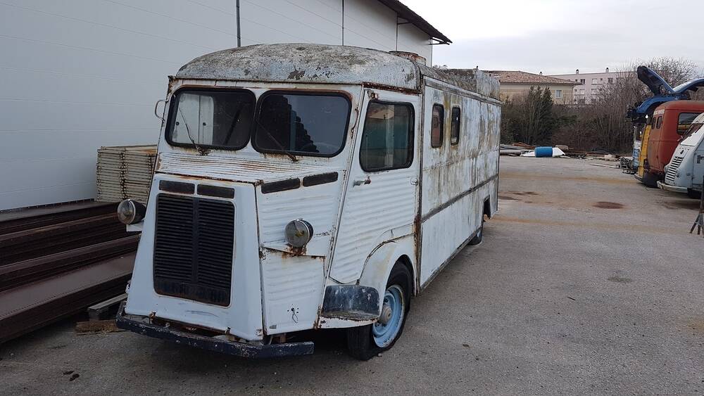 Un vieux fourgon Citroën Type H en tôle ondulée, garé dans la cour